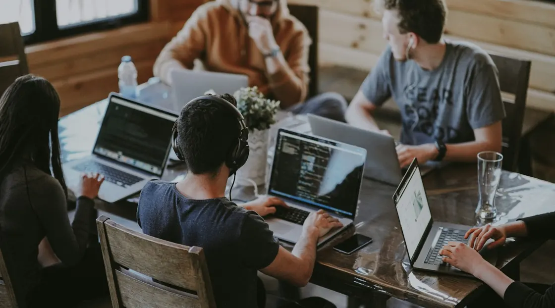 A collaborative team working together around laptops and a shared table